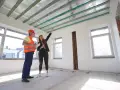 Inżynier i kobieta omawiają projekt podwieszanego sufitu w nowym budynku.