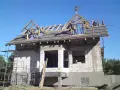 Budowa domu z bloczków, na dachu widać drewnianą konstrukcję i ozdobną wiechę.