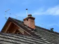Dach z drewnianymi gontami, komin z cegły i instalacja piorunochronu chroniąca przed burzą.