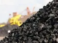 Góra węgla kamiennego, w tle maszyny górnicze. Zastanawiasz się, ile kosztuje tona węgla?