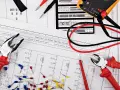 Narzędzia i schemat instalacji elektrycznej: kombinerki, obcinaczki, multimetr i złączki kablowe.