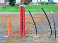 Przygotowania do wylania płyty fundamentowej: pomarańczowa rura i czerwone peszle z kablami na siatce zbrojeniowej.