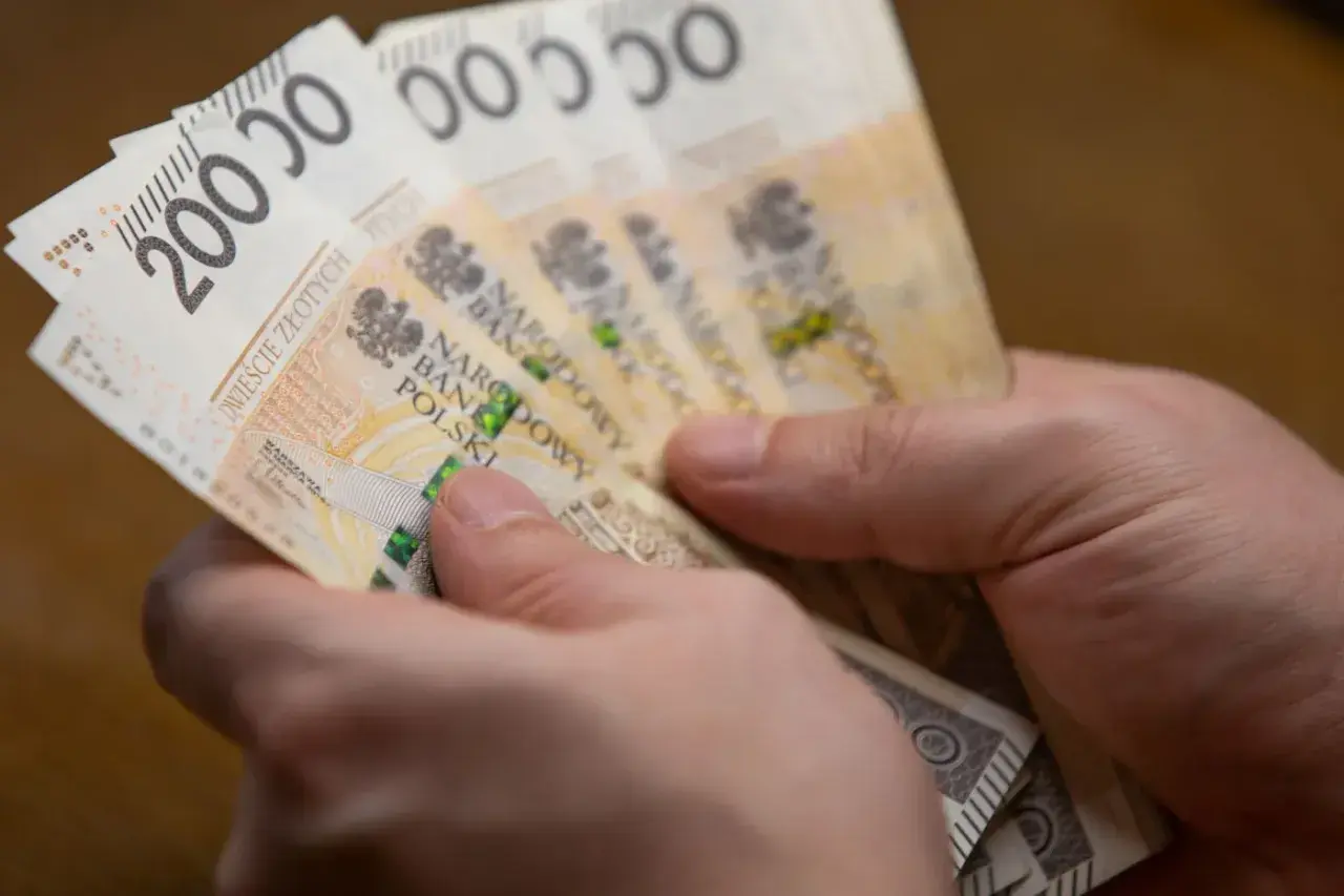 Dwie ręce trzymają plik banknotów 200 zł. Może to być zapłata za podatek ETS2.