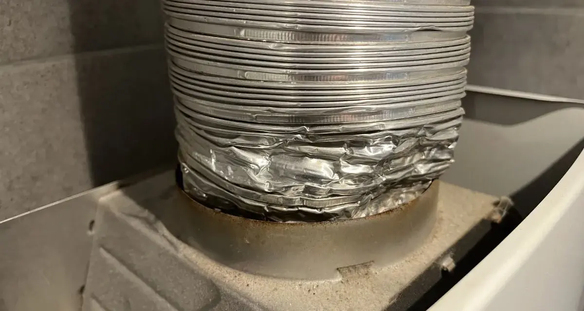 Zgnieciona, aluminiowa rura spalinowa podłączona do urządzenia. Montaż rury spalinowej do junkersa wymaga uwagi, by uniknąć takich uszkodzeń.