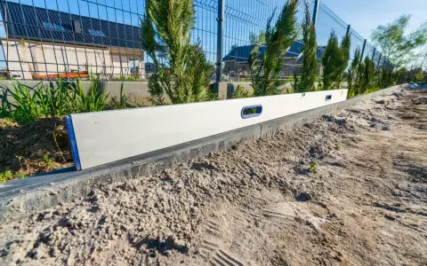 Poziomica na krawężniku, świadcząca o precyzyjnej niwelacji terenu pod przyszły ogród.