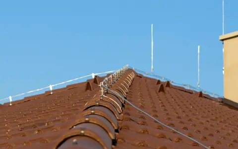Nowy dach z brązowej dachówki, na którym zamontowano nowoczesną instalację odgromową, chroniącą przed burzami.