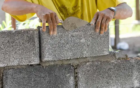 Budowniczy układa bloczki betonowe fundamentowe, tworząc solidną podstawę.