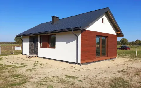 Nowy, nowoczesny dom do 70m2 z drewnianą elewacją i dużymi oknami, gotowy na przyjęcie mieszkańców.