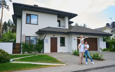 Szczęśliwa rodzina przed nowoczesnym domem. Realizacja marzeń o własnym M, gdzie koszt budowy domu 100m2 jest w zasięgu ręki.