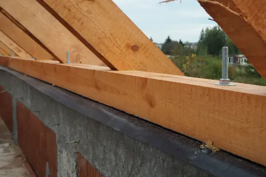 Drewniana murłata przykręcona do betonowego wieńca, podpora dla krokwi dachowych.