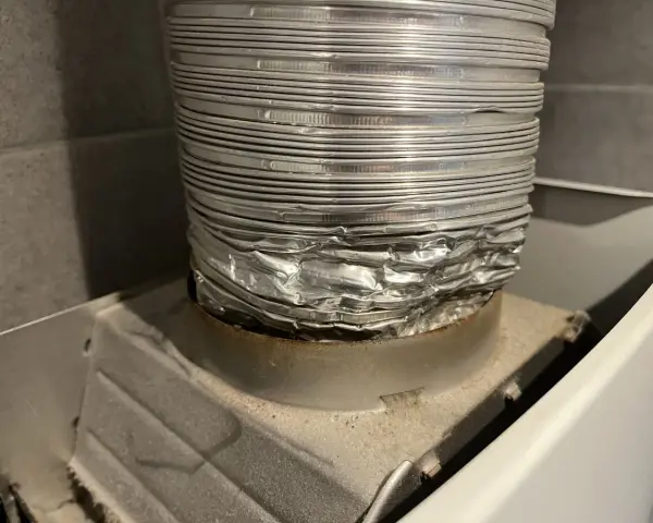 Zgnieciona, aluminiowa rura spalinowa podłączona do urządzenia. Montaż rury spalinowej do junkersa wymaga uwagi, by uniknąć takich uszkodzeń.