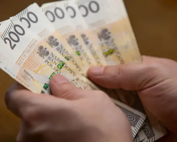 Dwie ręce trzymają plik banknotów 200 zł. Może to być zapłata za podatek ETS2.