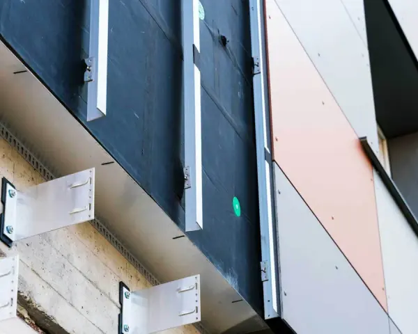 System mocowania elewacji wentylowanej. Metalowe wsporniki przytwierdzone do betonowej ściany, tworzące przestrzeń dla izolacji i wentylacji.