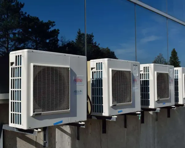 Kilka jednostek zewnętrznych klimatyzatorów Fujitsu zamontowanych na ścianie budynku. Zastanawiasz się, jaka pompa ciepła do domu 130m2?