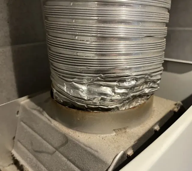 Zgnieciona, aluminiowa rura spalinowa podłączona do urządzenia. Montaż rury spalinowej do junkersa wymaga uwagi, by uniknąć takich uszkodzeń.