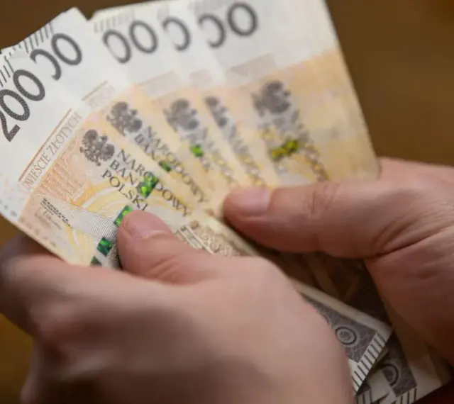 Dwie ręce trzymają plik banknotów 200 zł. Może to być zapłata za podatek ETS2.