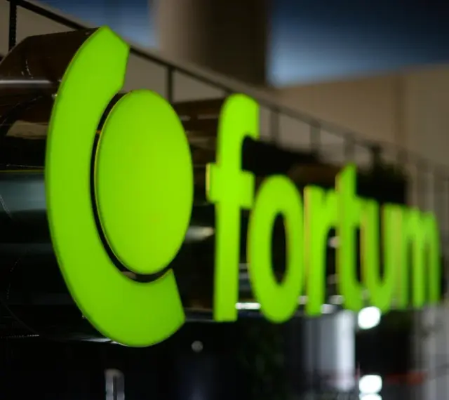Jasnozielone, podświetlane logo Fortum Energia na metalowej konstrukcji.