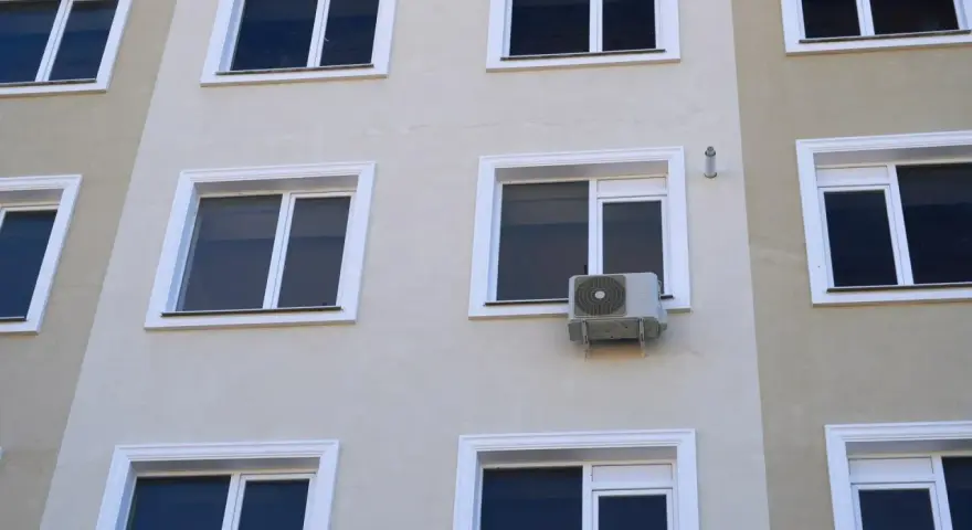 Klimatyzacja w bloku, zamontowana na ścianie między oknami, zapewnia komfort mieszkańcom.