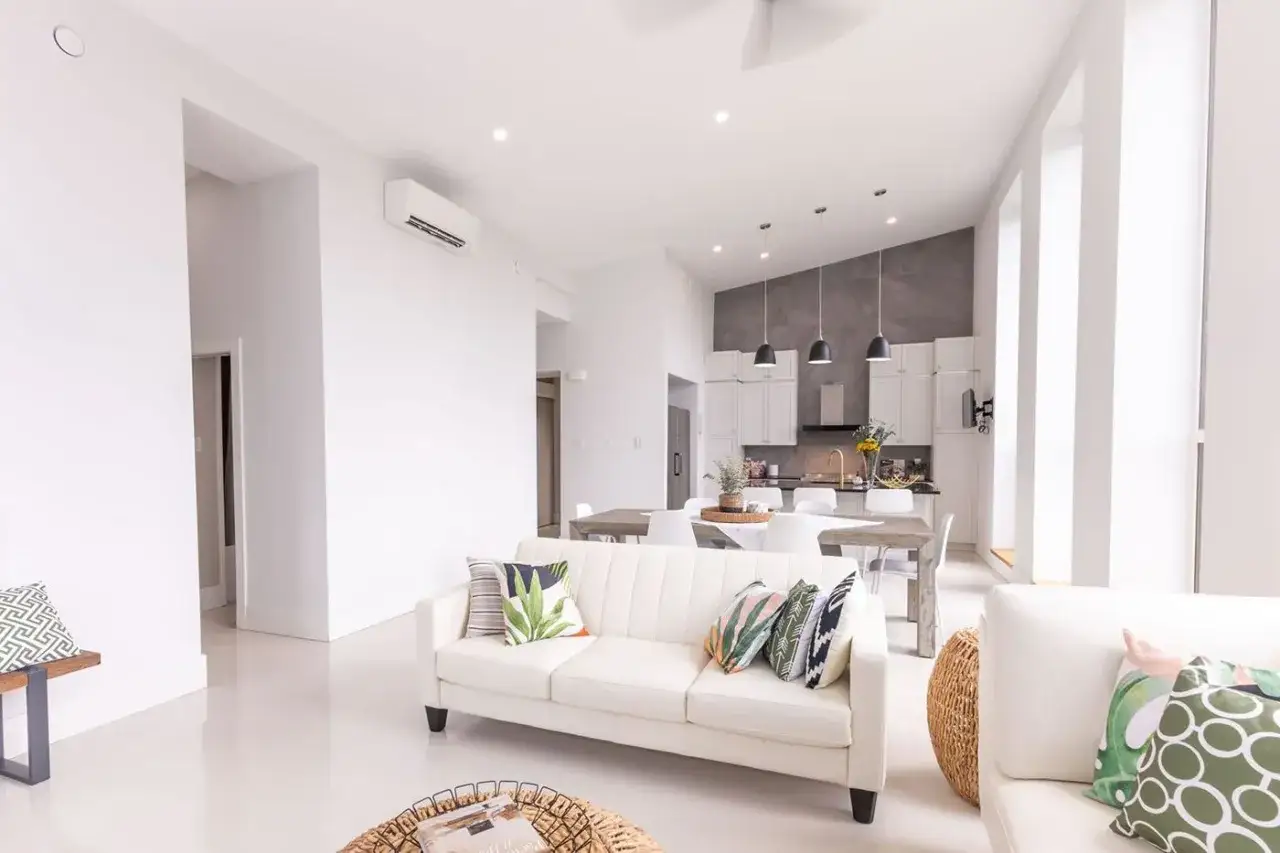 Nowoczesny salon z kuchnią. Zastanawiasz się, jaka pompa ciepła do domu 130m2? Klimatyzator na ścianie sugeruje komfortowe ogrzewanie i chłodzenie.